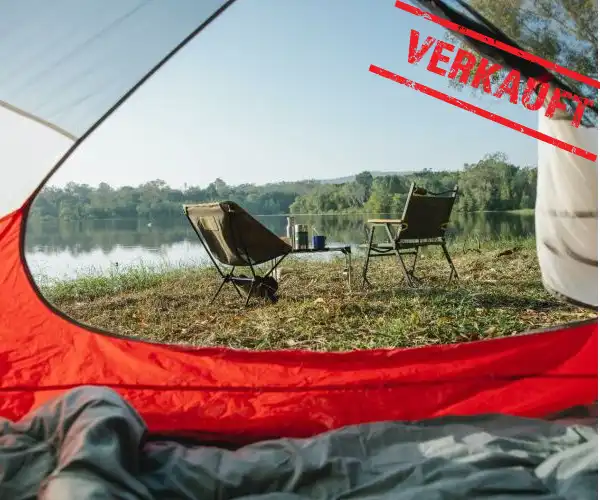 Blick aus einem Zelt am See auf zwei Camping-Stühle