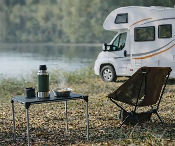 Wohnmobil am See mit Campingstuhl und Tisch. Beitragsbild für ein Angebot eines Campingplatzes in Thüringen von CampConsult, Berlin